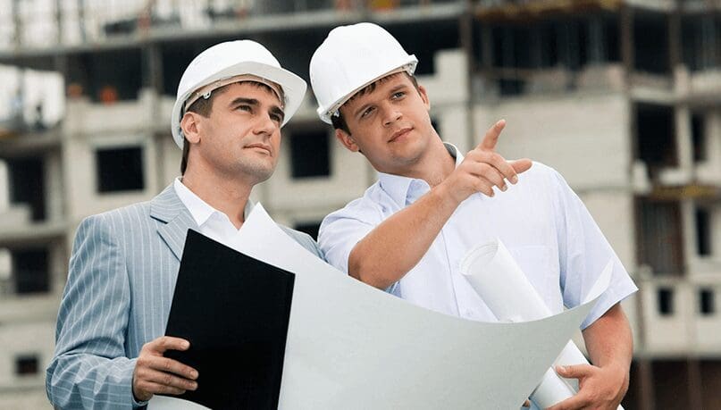 Two men in hard hats looking at a building plan.